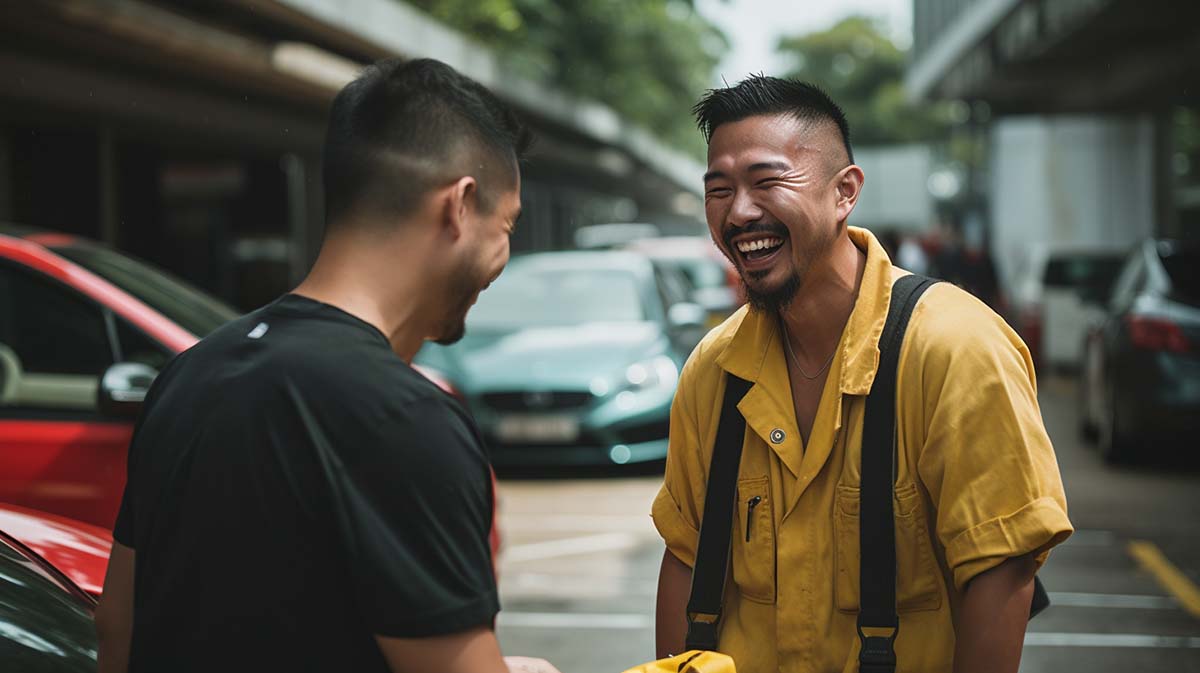 A happy mechanic in yellow overall, laughing with his friend wearing a black T-shirt.